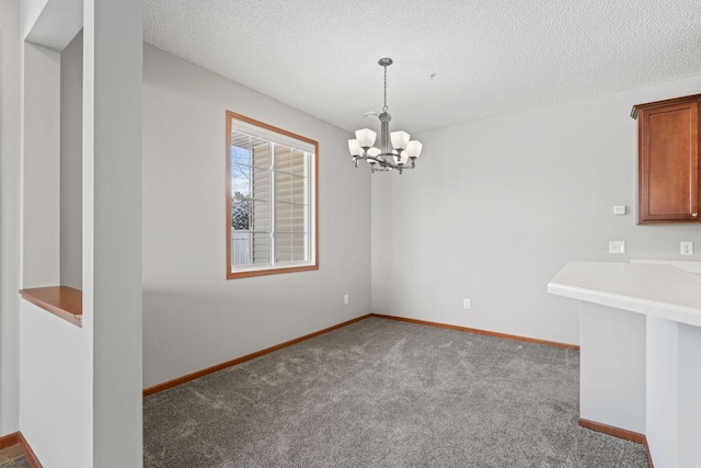 unfurnished dining area with a textured ceiling, an inviting chandelier, and carpet flooring