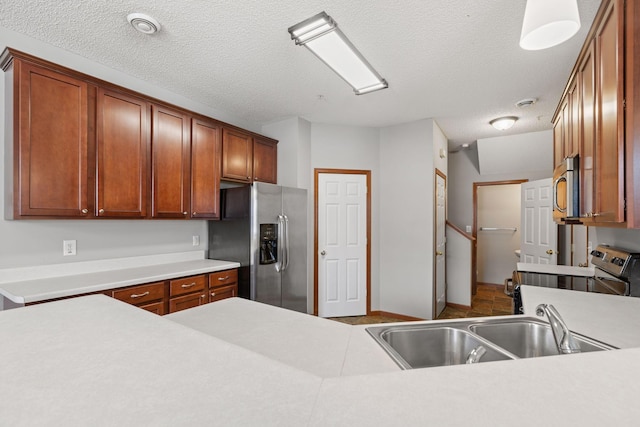 kitchen featuring sink, a textured ceiling, pendant lighting, and appliances with stainless steel finishes