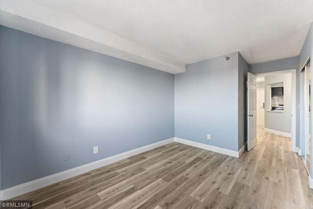 unfurnished room with a textured ceiling and light hardwood / wood-style flooring