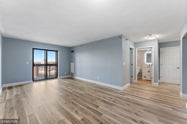 spare room featuring a textured ceiling and light hardwood / wood-style flooring