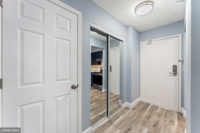 doorway featuring a textured ceiling and light wood-type flooring