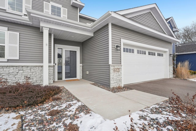 snow covered property entrance featuring a garage