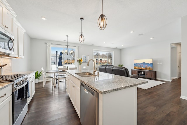 kitchen with sink, an island with sink, pendant lighting, and appliances with stainless steel finishes