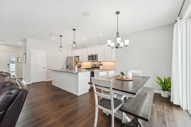 dining space featuring sink, an inviting chandelier, and dark hardwood / wood-style flooring