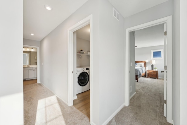 hallway featuring washer / dryer and light carpet