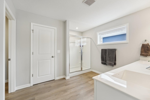 bathroom featuring hardwood / wood-style floors, walk in shower, and vanity