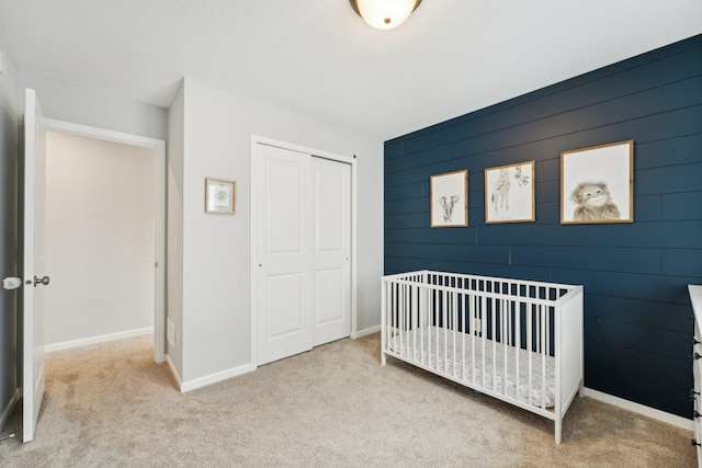 bedroom featuring a crib, light colored carpet, and a closet