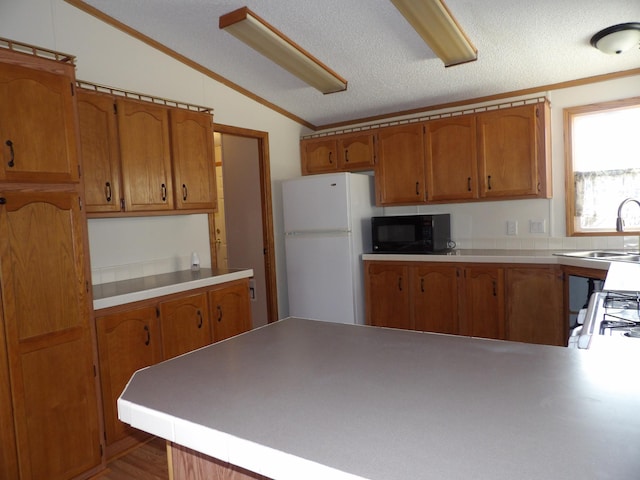 kitchen featuring kitchen peninsula, sink, white appliances, a textured ceiling, and lofted ceiling