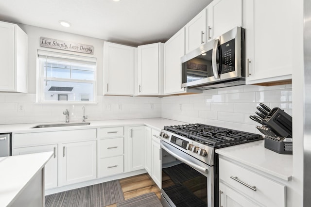 kitchen with white cabinetry, appliances with stainless steel finishes, sink, and decorative backsplash