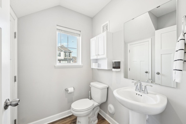 bathroom with hardwood / wood-style flooring, lofted ceiling, toilet, and sink