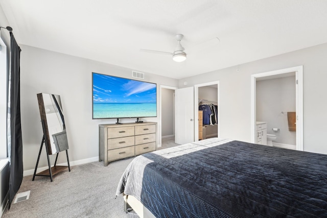 carpeted bedroom with ensuite bathroom, a walk in closet, and ceiling fan