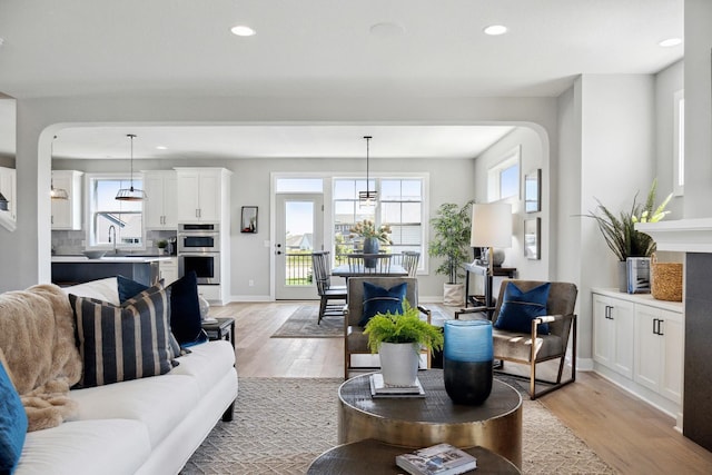 living room with light wood-type flooring, a wealth of natural light, and a notable chandelier