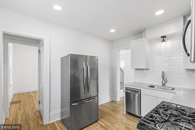 kitchen featuring white cabinets, sink, stainless steel appliances, and light hardwood / wood-style floors