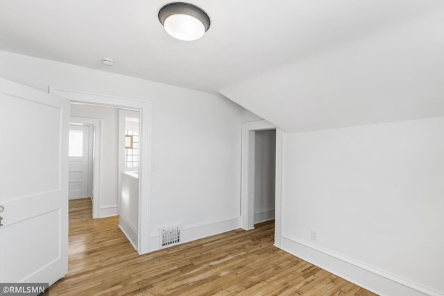 additional living space featuring lofted ceiling and light hardwood / wood-style flooring