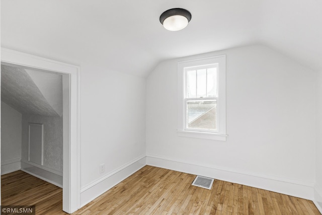 additional living space featuring lofted ceiling and light hardwood / wood-style flooring