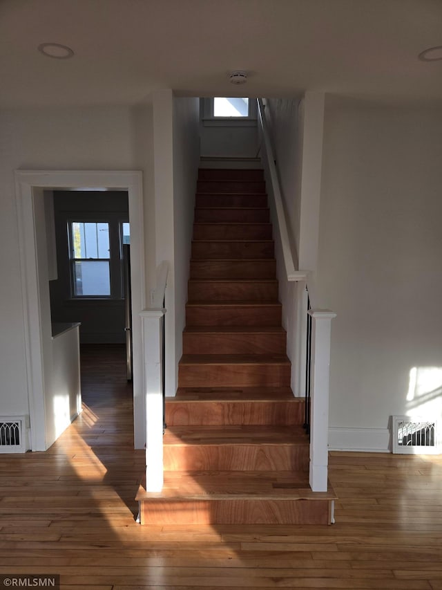 stairway with hardwood / wood-style flooring and a wealth of natural light