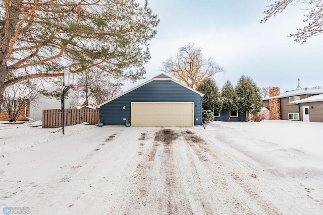 view of snow covered exterior with a garage and an outbuilding