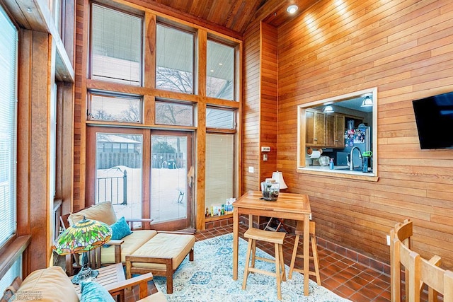 interior space featuring wood ceiling, wooden walls, and a high ceiling