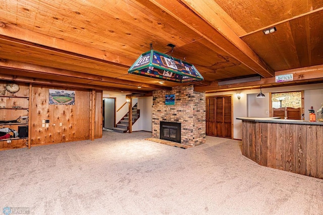 unfurnished living room featuring wooden walls, carpet flooring, a fireplace, wooden ceiling, and beamed ceiling