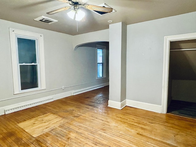 empty room featuring ceiling fan, a baseboard heating unit, and light hardwood / wood-style floors