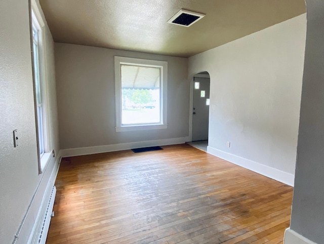 unfurnished room featuring light hardwood / wood-style floors and baseboard heating