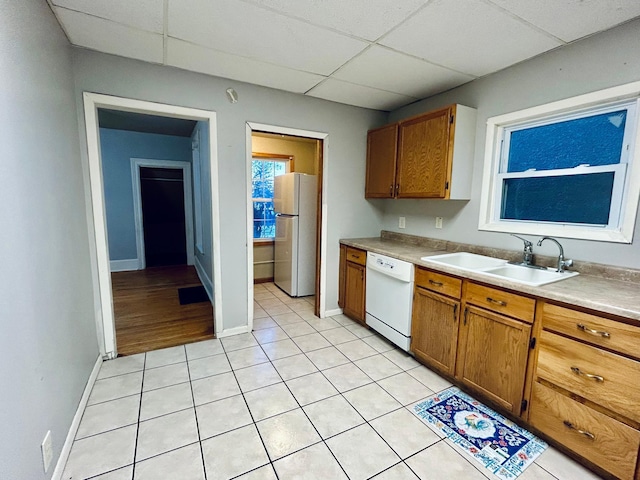 kitchen featuring sink, white appliances, a drop ceiling, and light tile patterned floors