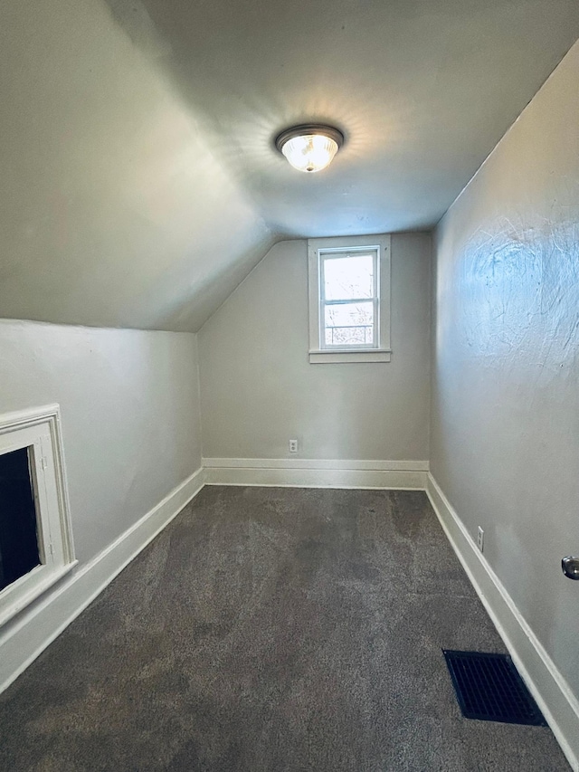 bonus room with dark colored carpet and lofted ceiling