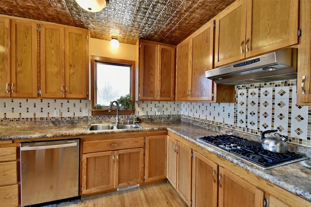 kitchen with stainless steel appliances, sink, light hardwood / wood-style flooring, and decorative backsplash