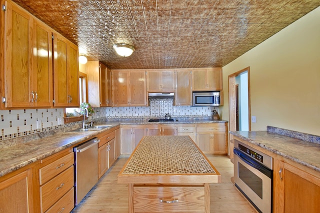 kitchen with brick ceiling, sink, a center island, light wood-type flooring, and stainless steel appliances