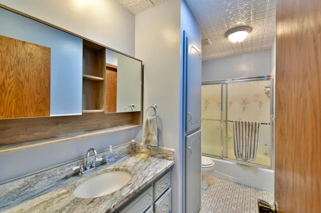 full bathroom featuring vanity, tile patterned flooring, toilet, and combined bath / shower with glass door