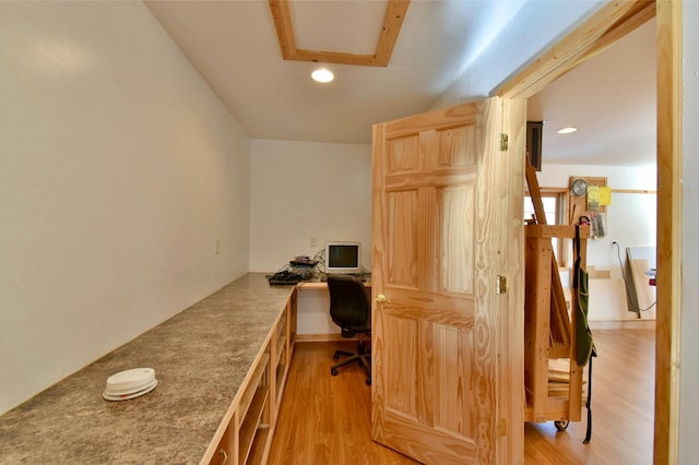 office space with built in desk and light wood-type flooring