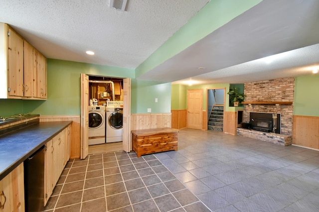 laundry area with dark tile patterned flooring, a textured ceiling, washing machine and clothes dryer, and wood walls