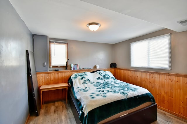 bedroom with wooden walls and light hardwood / wood-style flooring