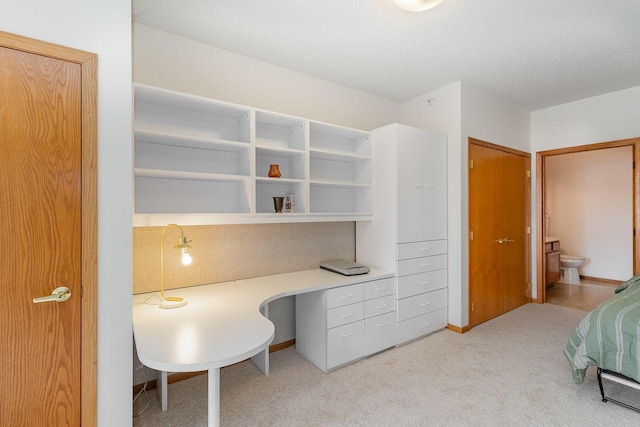 office area with light carpet, built in desk, and a textured ceiling