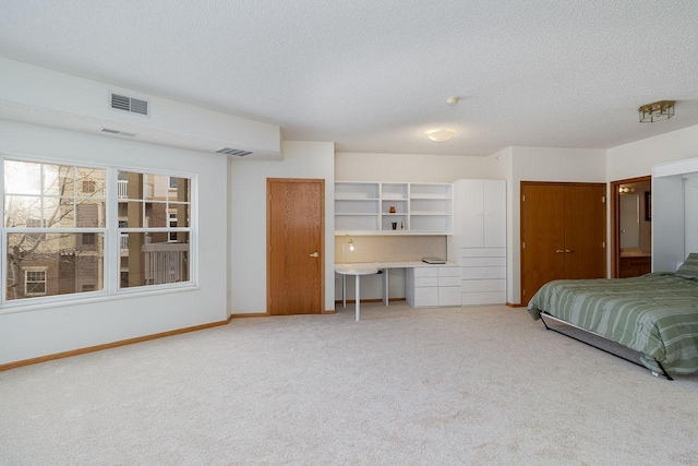 carpeted bedroom featuring two closets, built in desk, and a textured ceiling