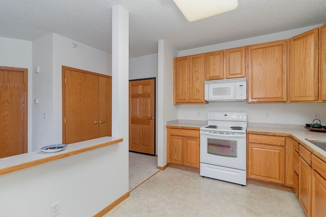 kitchen featuring white appliances, sink, and a textured ceiling