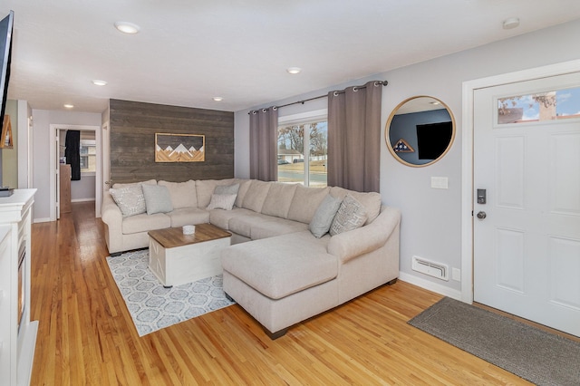 living room with recessed lighting, an accent wall, visible vents, baseboards, and light wood-style floors