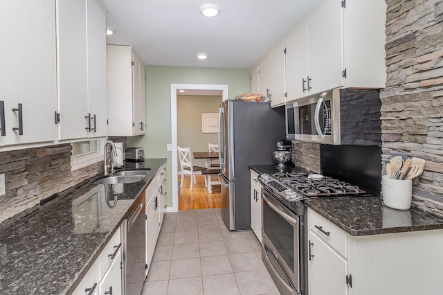 kitchen with light tile patterned floors, decorative backsplash, appliances with stainless steel finishes, white cabinets, and a sink