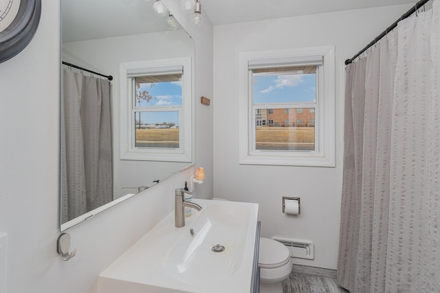 bathroom with toilet, visible vents, wood finished floors, and vanity