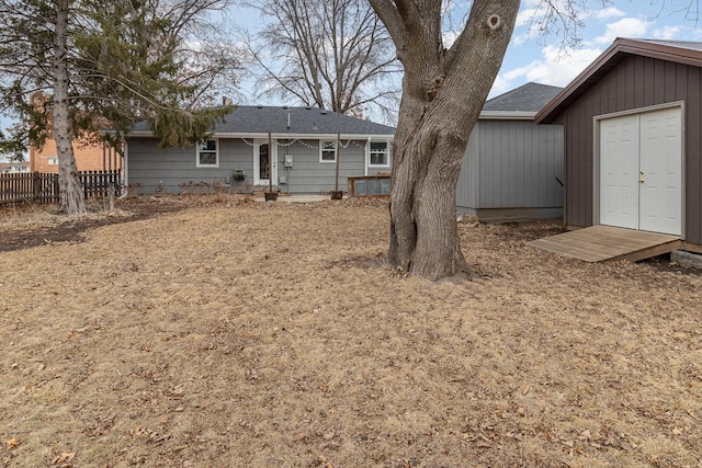 rear view of house with fence, an outdoor structure, and a storage shed