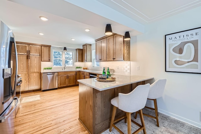 kitchen featuring a kitchen bar, sink, tasteful backsplash, appliances with stainless steel finishes, and kitchen peninsula