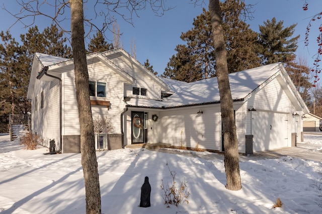 snow covered back of property featuring a garage