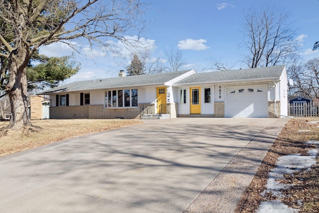 ranch-style house with brick siding, roof with shingles, a chimney, a garage, and driveway