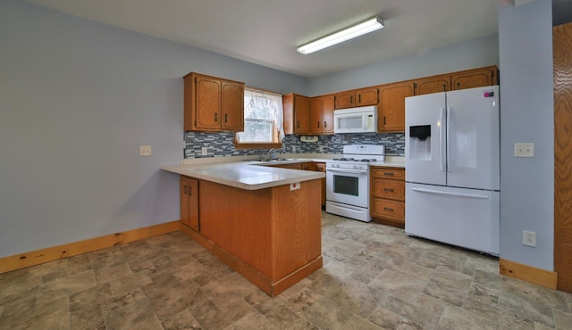 kitchen featuring brown cabinets, backsplash, a peninsula, and white appliances