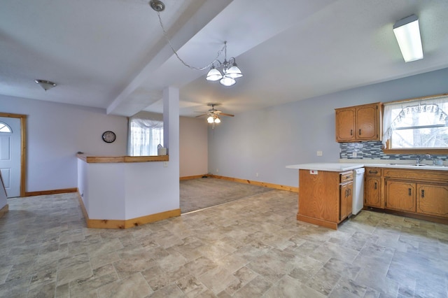 kitchen with light countertops, a sink, a peninsula, white dishwasher, and brown cabinets