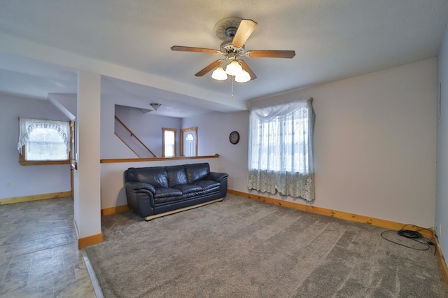 unfurnished living room with baseboards, carpet floors, and ceiling fan