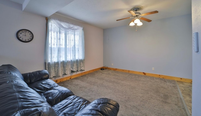living area featuring baseboards, ceiling fan, and carpet