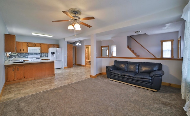 living room featuring baseboards, stairway, a ceiling fan, and light colored carpet