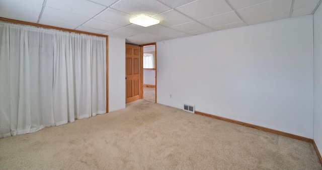 spare room with a drop ceiling, carpet floors, baseboards, and visible vents