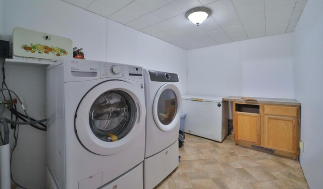 clothes washing area featuring cabinet space, independent washer and dryer, and stone finish floor
